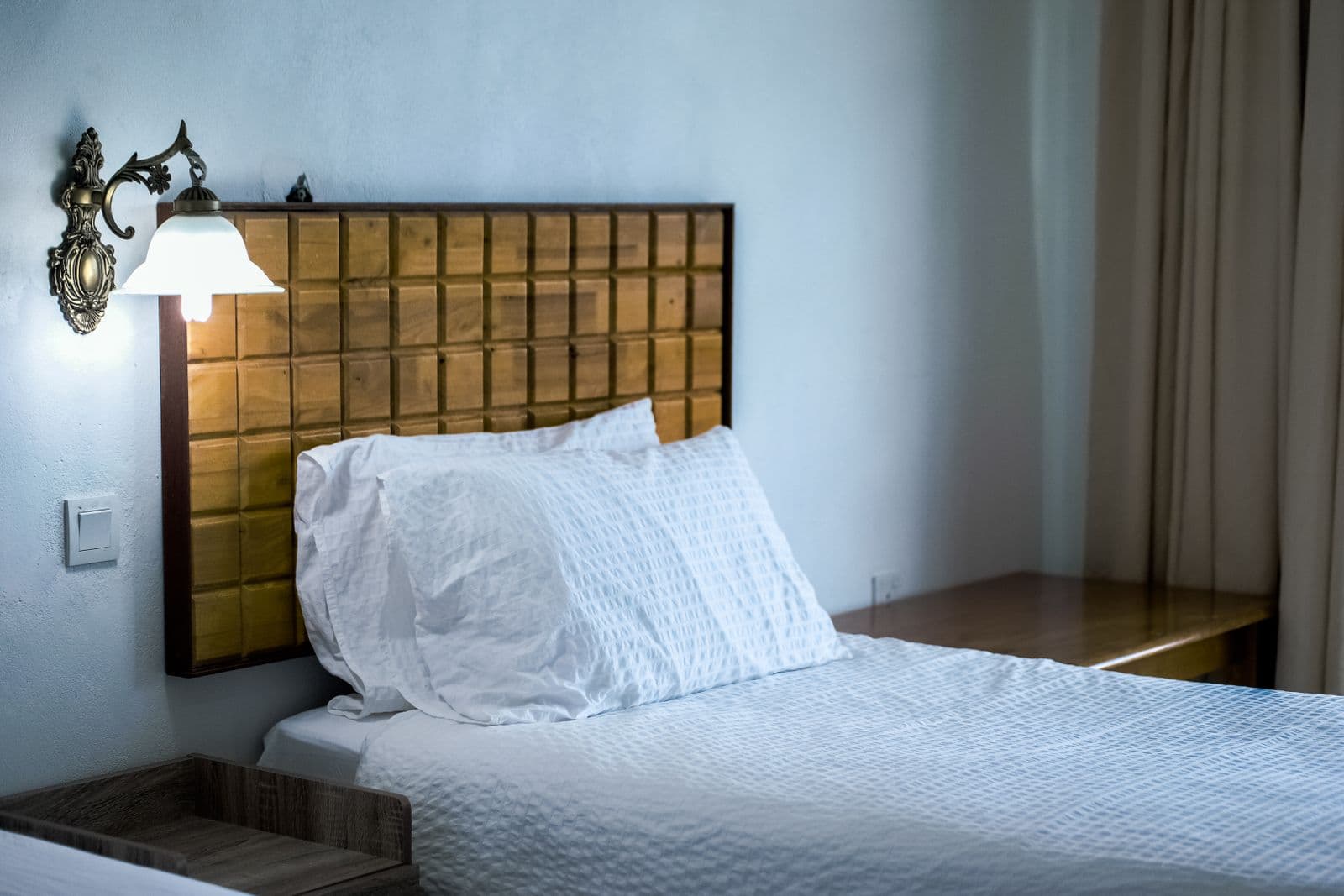 Neatly made bed with a wooden headboard in a bright, guest-ready bedroom